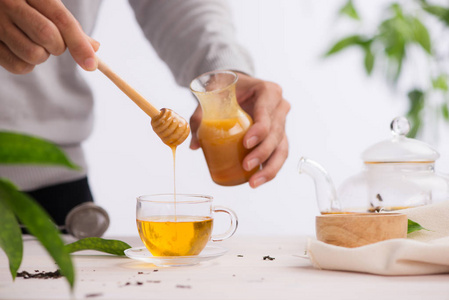 裁剪图像的 arista 浇注蜂蜜入杯茶