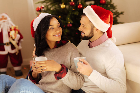 幸福的夫妇，在圣诞老人的帽子，羡慕地看着对方