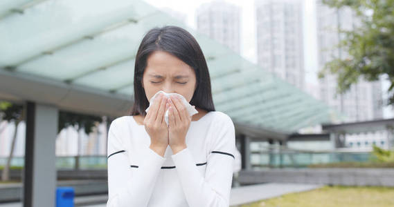 年轻女人打喷嚏在室外