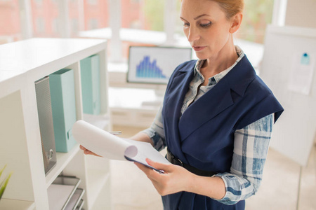 中年秘书在办公室工作期间阅读财务文件照片