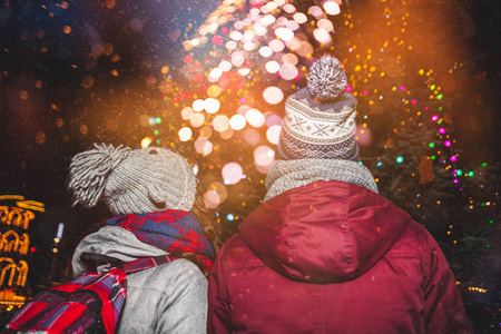 在传统的圣诞集市上下雪的夜晚, 情侣穿暖和的冬衣