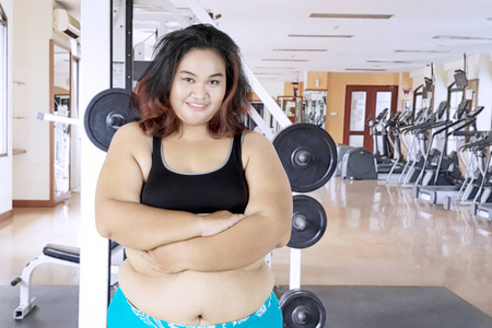肥胖妇女折叠她的胳膊在健身房中心