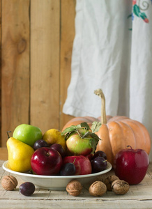 秋天的静物与苹果 梨 李子 南瓜和核桃木的背景上。乡村风格，选择性焦点