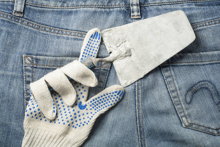工作手套与抹灰工具的背景下的牛仔裤。顶部视图