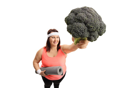 超重妇女与运动垫和花椰菜