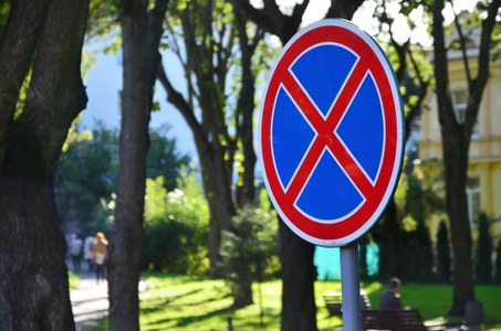 在蓝色背景上有一个红色十字的圆形路标。标志意味着禁止停车