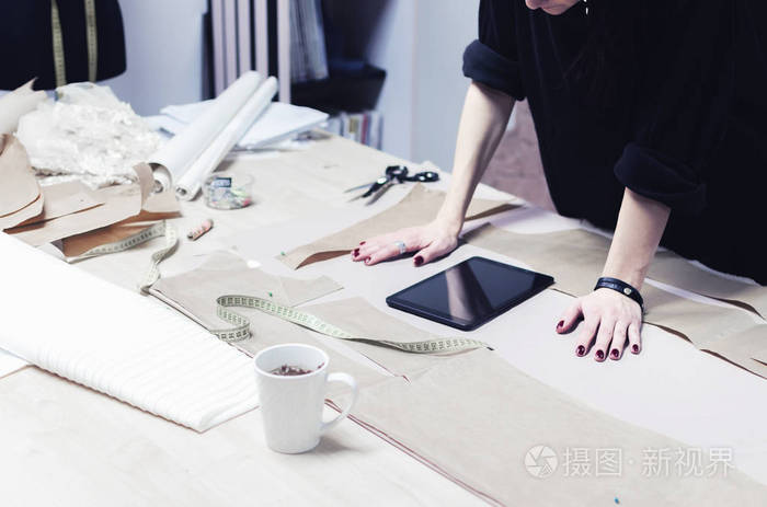 女性时装设计师与平板电脑在裁缝店工作