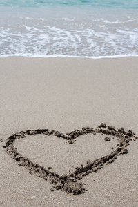 画在沙滩上的沙子与海上的泡沫和波上, 直的心