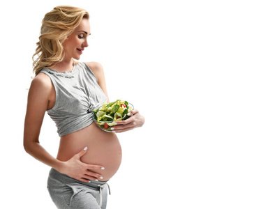 美丽的怀孕妇女举行有机沙拉。孕产妇期望健康饮食