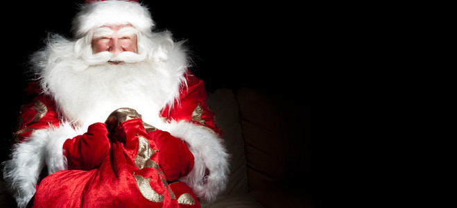 圣诞老人坐在圣诞房间和寻找进袋子