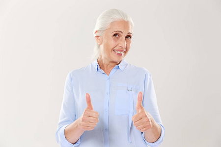 快乐的老妇人的画像在蓝色衬衣显示竖起大拇指 g