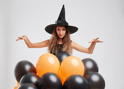 可爱的女巫女孩与橙色, 黑色的气球,在明亮的背景上.万圣节装饰概念.
