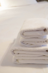 一堆毛巾放在酒店房间的床上