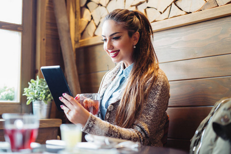 美丽的年轻女实业家在咖啡馆, 使用数字平板电脑和喝咖啡微笑