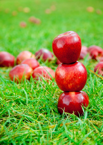 三个红苹果堆在草地上