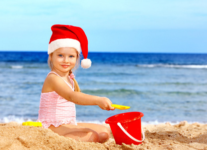 戴圣诞帽的孩子在海滩上玩。