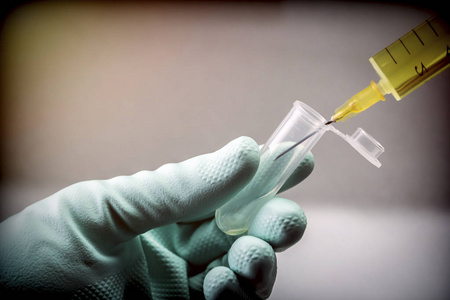 科学家与绿色乳胶手套操作小瓶和注射器在实验室, 概念图象