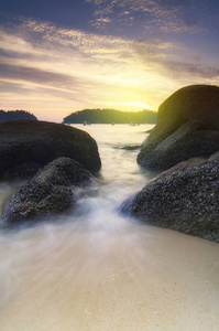 金色夕阳背景下的田园诗般的热带风光, 松软的海浪拍打着沙滩上的岩石