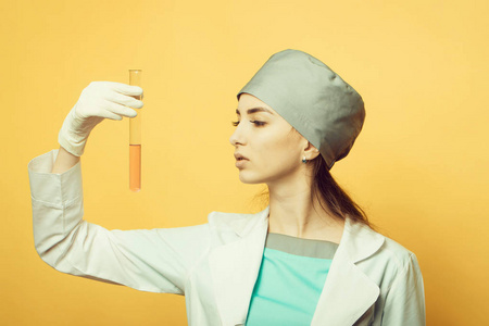 在医护人员制服与瓶的演播室上橙色背景化学实验室科学家女医生