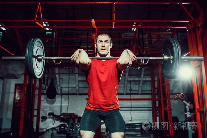 肌肉的健美男子做硬拉杠铃在他头上现代化的健身中心功能训练