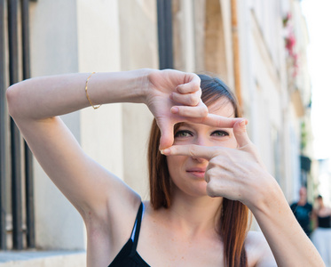 年轻女子在取景器的手势中专注地观看照片