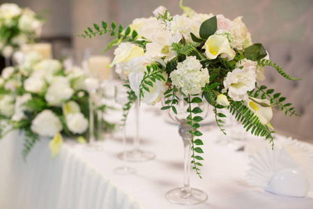 内部的婚礼装饰。桌上白花。用水晶眼镜为桌子服务