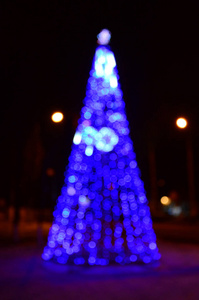 新的一年树模糊的照片。许多圆形的灯在蓝色