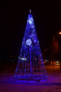 新年树的照片。许多蓝色的圆形灯位于锥形框架上。