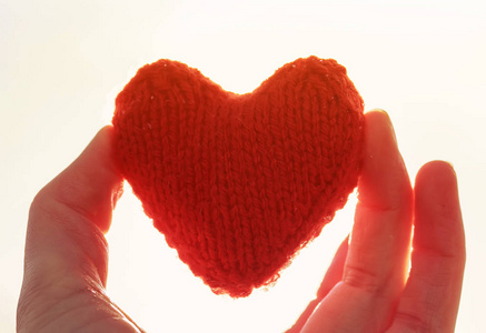 红针织的心保持我的手指在阳光明媚的背景照片