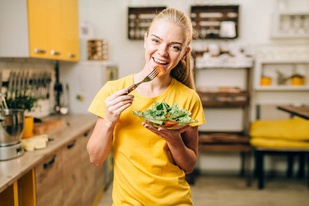 快乐的女人吃沙拉在厨房, 健康的生物食品烹饪。素食饮食