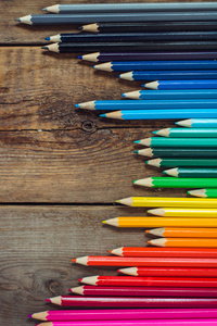 在位于木制的桌子上边缘的梯度秩序的彩色的铅笔。学校的概念。复制空间