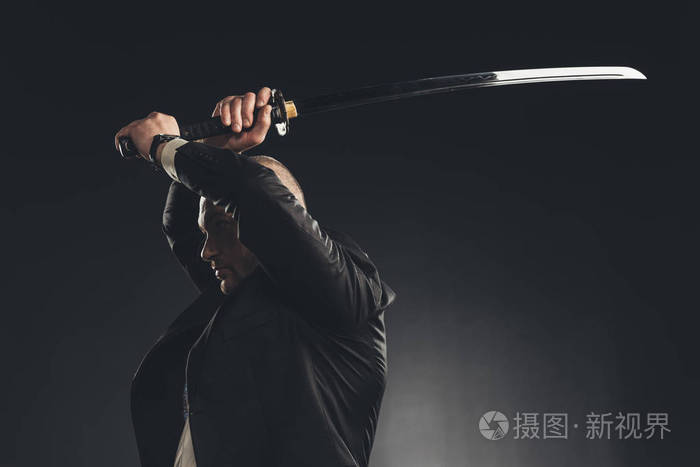 在西装的人的侧面看, 用武士刀剑在黑色孤立的命中照片-正版商用图片