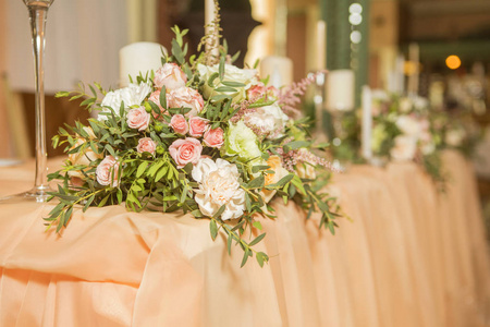 婚礼桌上装饰满是玫瑰和洋花蜡烛和桃色面料。豪华的餐厅内饰。室内.复制空间