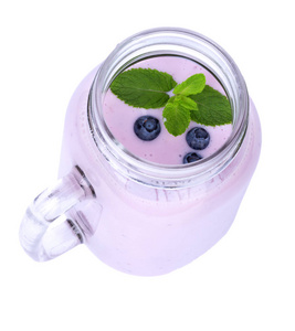 在一个白色的背景下, 一个满是淡紫色的蓝莓的小浆果和新鲜薄荷的梅森罐子上面的景色。健康早餐的营养鸡尾酒