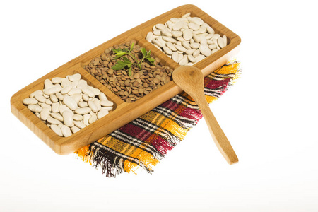 生白芸豆扁豆和大米在木制盘子里用木勺和五颜六色的棉餐巾在白色背景上隔离, 顶视图。宏, 关闭
