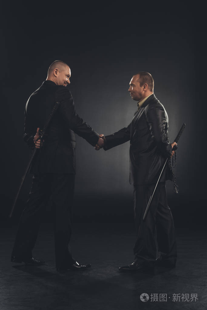 侧视图的黑社会成员握手与刀背后孤立黑色照片-正版商用图片03kohv-摄