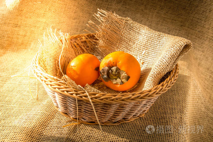 美味成熟的柿子果在篮子用粗麻布织品与早晨阳光