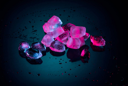 粉红色融化的冰块在黑色与水滴关闭照片
