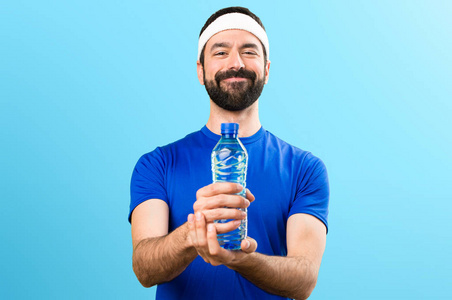 快乐滑稽的运动员与一瓶水在五颜六色的 backgro