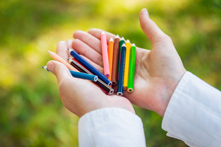 女性手用五颜六色的铅笔在公园里