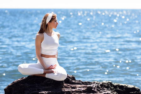 做瑜伽在海滩穿白色衣服的年轻女人