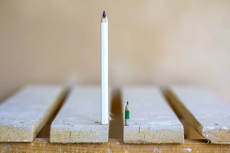 木制木板桌上有一只小的和一支大铅笔