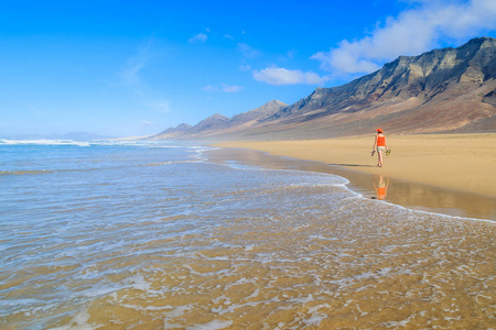在 Cofete 海滩和火山山漫步在汉迪亚半岛, 岛, 西班牙加那利群岛的背景上的年轻女子游客