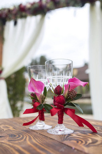 一套婚礼眼镜与葡萄酒颜色的花朵和丝带的木质表面 表。户外.复制空间