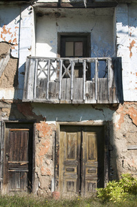 陈旧的废弃腐朽的垃圾乡村摇摇欲坠的房子粘土倒塌的门面, 忽视木窗, 阳台和门