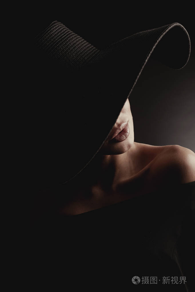 戏剧工作室肖像的优雅的女人在黑色宽帽和黑色礼服.隐藏的半边脸