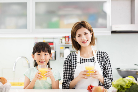 快乐的母亲和孩子在厨房喝果汁