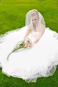 美丽的新娘在婚礼当天在草地上摆姿势