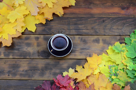 一杯茶, 在一组黄色的秋天落叶的背景表面上的深棕色天然木板