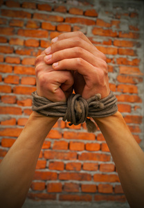 双手用绳子绑在砖墙上